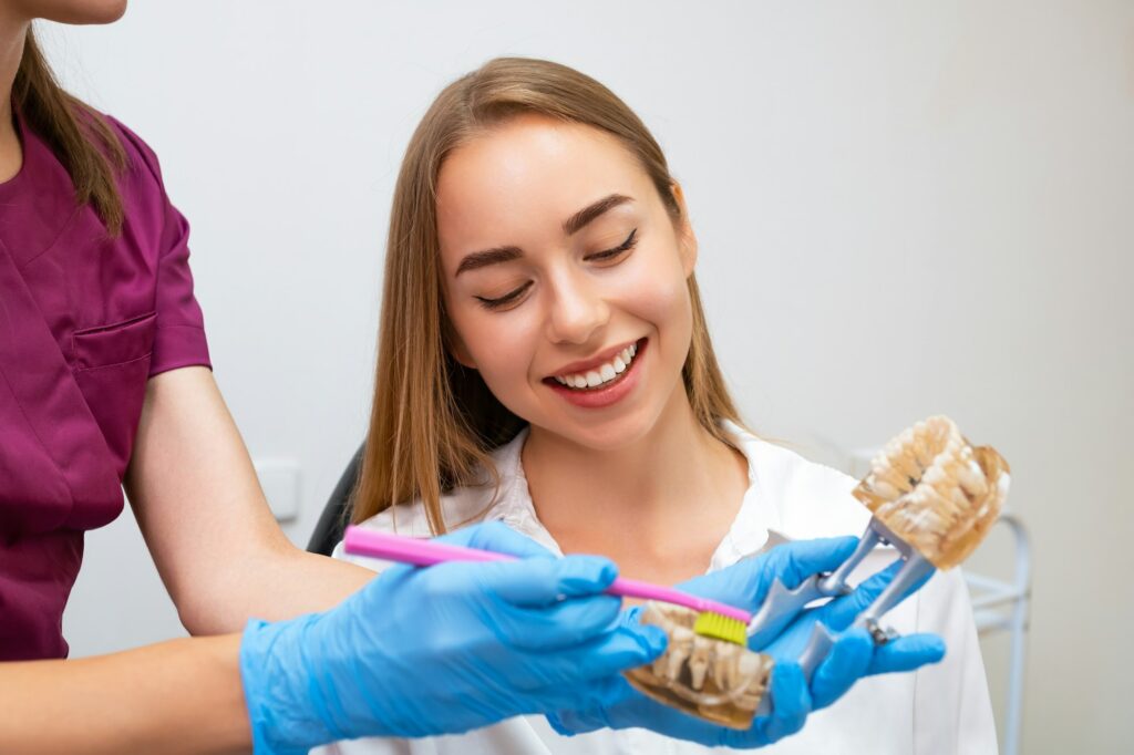 Dental hygienist demonstrate young woman how to clean teeth